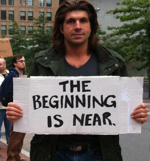 Garret John LoPorto holding a sign reading The Beginning Is Near